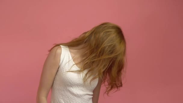 Beautiful teenage girl with red blowing hair and blue eyes on pink background - Πλάνα, βίντεο