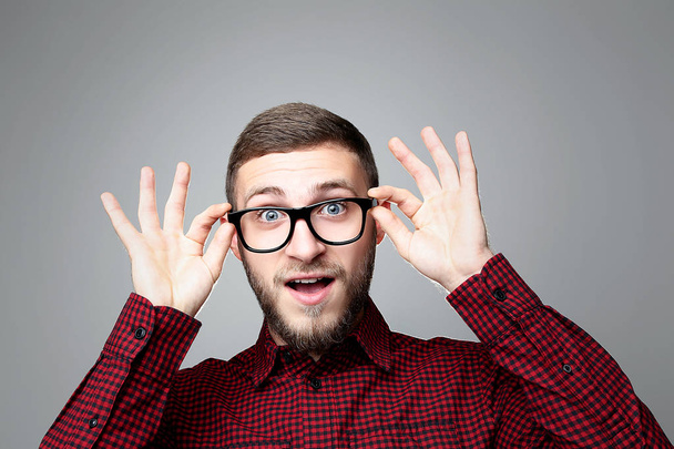 Portrait of young surprised man in glasses on grey background - Foto, Imagem