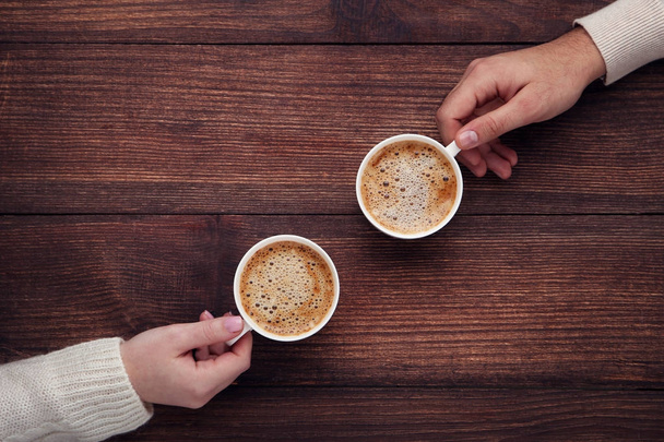 weibliche und männliche Hand mit Kaffeebechern auf Holztisch - Foto, Bild
