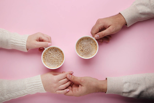 Θηλυκή και αρσενική χέρι που κρατά το άλλο και φλιτζάνια του καφέ - Φωτογραφία, εικόνα