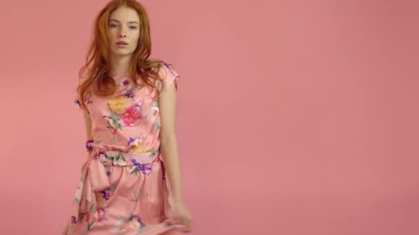 Portrait red-haired fashion model in pink dress on a pink background - Video, Çekim