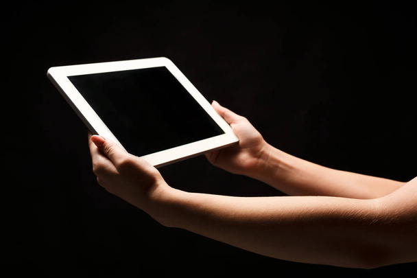 Mulher segurando tablet com tela em branco no fundo preto
 - Foto, Imagem