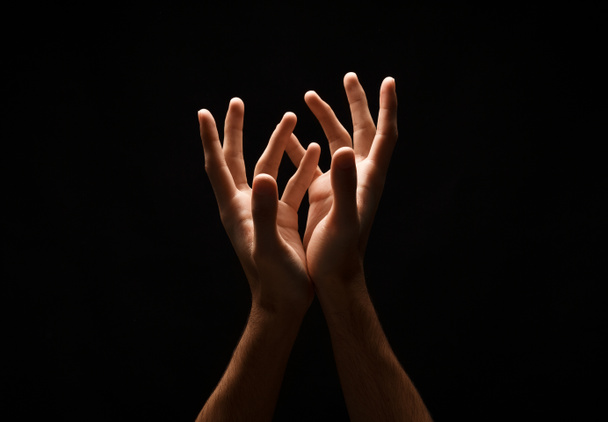 Чоловік тримає руки в загорнутій формі, вирізає на чорному
 - Фото, зображення