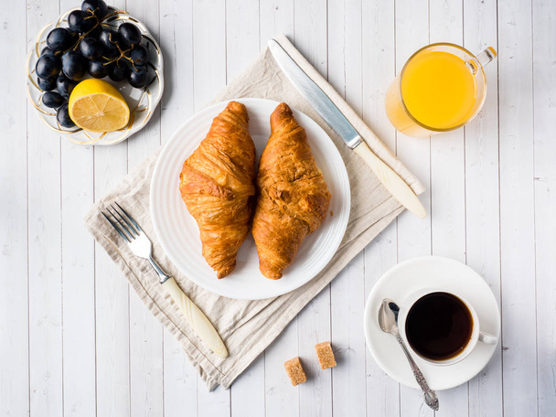 Breakfast on a White Table Coffee Croissant Orange juice Grapes Apple Chocolate - Фото, изображение