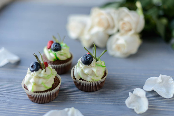 Tasty cupcakes adn roses on wooden table - Fotoğraf, Görsel