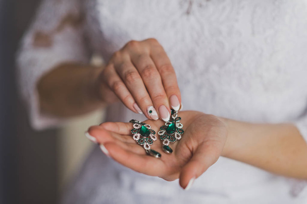 Earrings with green stones in the womens hands 8828. - Фото, зображення