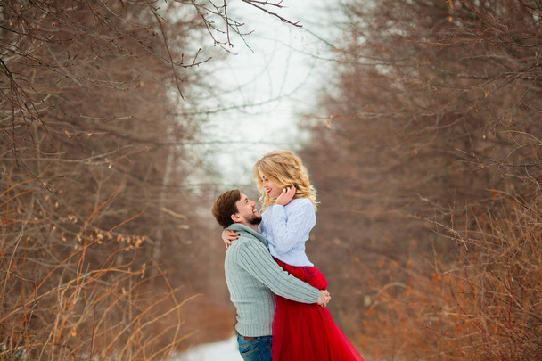 beautiful young couple in love in sweaters walking on snowy forest park - Foto, Imagen