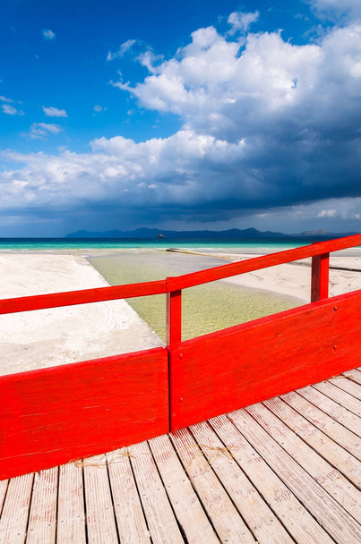 Pasarela roja de madera en la playa de Alcudia, Mallorca, España
 - Foto, Imagen