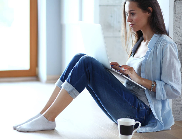 Young beautiful woman at home sitting on the floor with laptop. Young beautiful woman. - Foto, Imagen