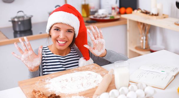 Happy young woman smiling happy having fun with Christmas preparations wearing Santa hat - Photo, Image
