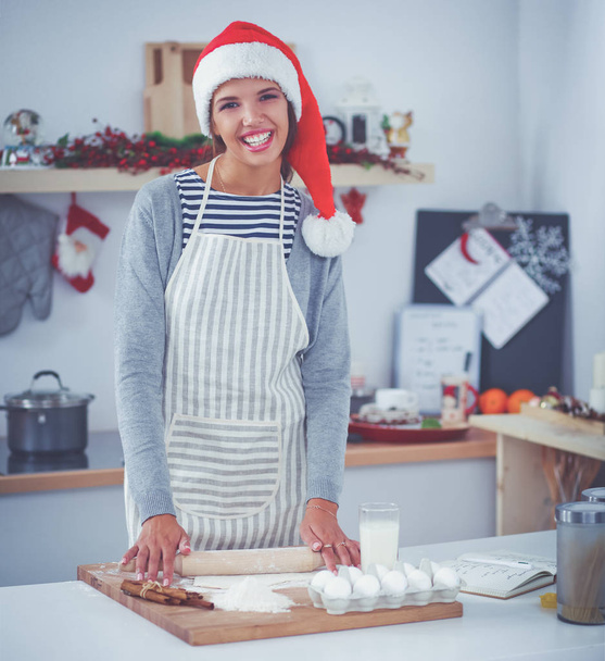 Happy young woman smiling happy having fun with Christmas preparations wearing Santa hat - 写真・画像