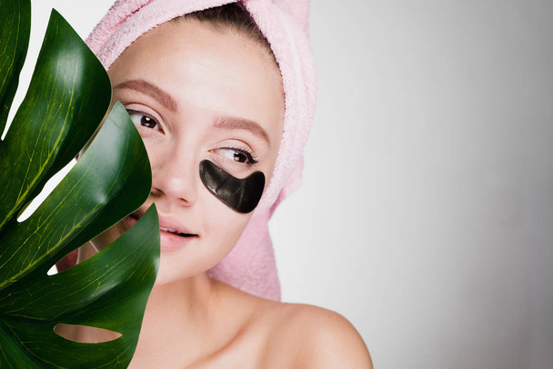 cute young girl with a pink towel on her head enjoying spa treatments, holding a green leaf - Fotoğraf, Görsel