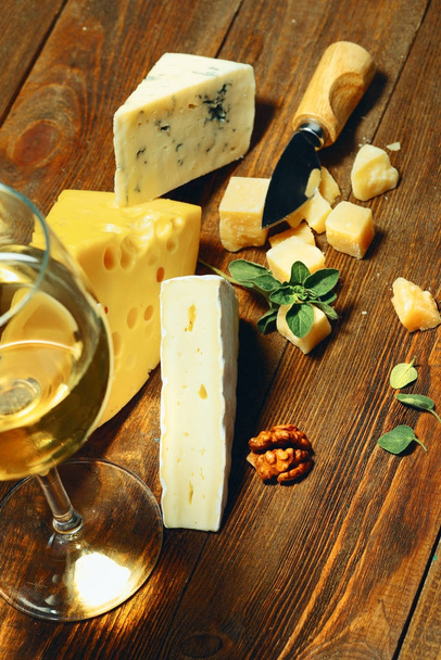 Fromage et vin dans un verre sur une planche de bois
. - Photo, image