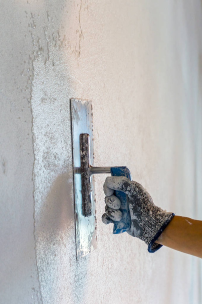 female hand with a trowel applying plaster during renovation work - Photo, Image