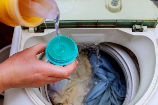 Vrouw hand gieten wasmiddel in de wasmachine waspoeder in de wasmachine - Foto, afbeelding