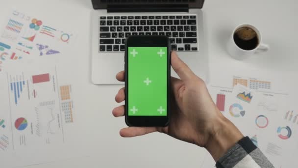 Επιχειρηματίας κρατώντας smartphone με πράσινη οθόνη chroma κλειδί στο φόντο λευκό γραφείο τραπέζι. - Πλάνα, βίντεο