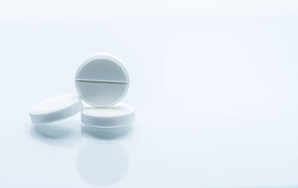 Макро знімок з трьох білих жувальних таблеток на білому тлі з тінями. Антациди таблетки для полегшення болю в шлунку від надлишку шлункової кислоти в шлунку. Концепція лікування виразки шлунка
. - Фото, зображення