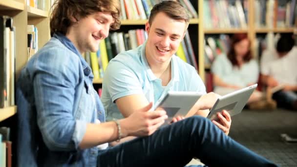 mannelijke klasgenoten sociale netwerken op tabletten in bibliotheek - Video