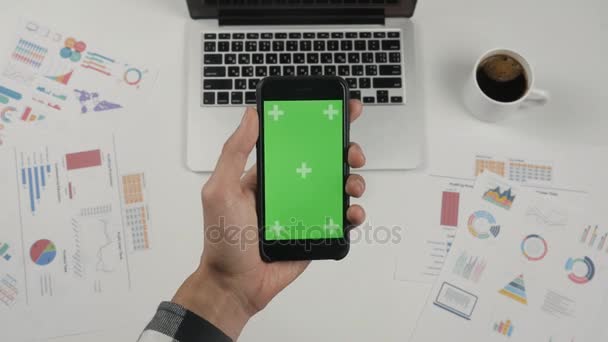 Επιχειρηματίας κρατώντας smartphone με πράσινη οθόνη στο φόντο λευκό γραφείο τραπέζι. - Πλάνα, βίντεο
