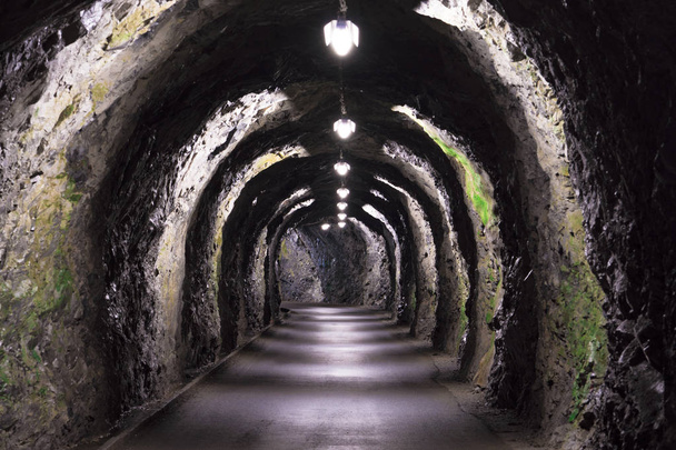 kapea vanha tunneli vuorten läpi Alpeilla perusvalaistuksella
 - Valokuva, kuva