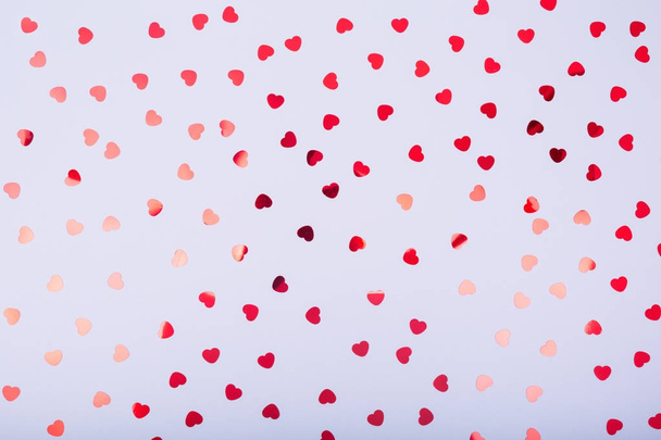 Grey background with red glitter heart confetti. Valentine day c - Zdjęcie, obraz