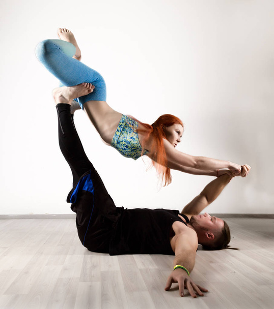 cara e mulher jovem fazendo exercícios de força em assanes de ioga. Conceito de Acroyoga
 - Foto, Imagem