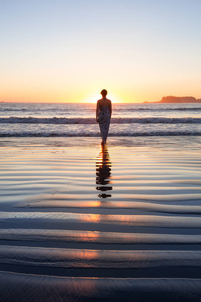 Rear view of the woman walking in the water of the ocean at sunset time  - Fotoğraf, Görsel