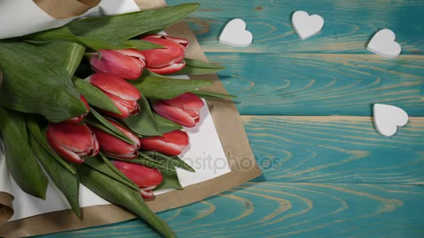 Bovenaanzicht van een bruiloft dag bericht en tulpen bloemen boeket op een houten tafel. Paar relatie concept. Huwelijk concept. Schot in 4 k - Video