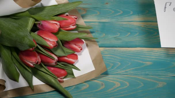 Draufsicht auf eine Verzeihungsbotschaft und Tulpenblumenstrauß auf einem Holztisch. Paarbeziehungskonzept. Schuss in 4 k - Filmmaterial, Video