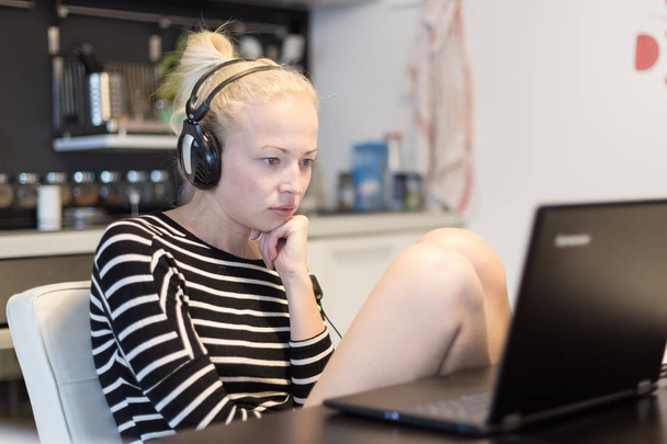 Adult woman in her casual home clothing working and studying remotely from her small flat late at night. - Photo, Image
