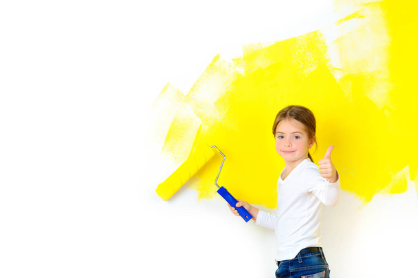 beautiful girl paints a roller with a wall in the room, smiling and shows class - Foto, imagen