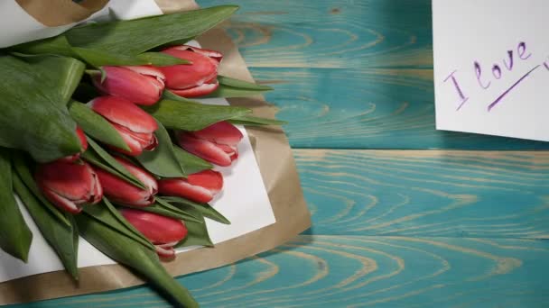 Bovenaanzicht van een I love you bericht opmerking en tulpen bloemen boeket op een houten tafel. Paar relatie concept. St: Valentijn met s. Schot in 4 k - Video