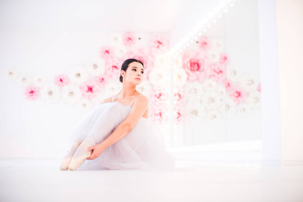 Genç ve inanılmaz güzel balerin ışıkla dolu beyaz bir stüdyoda poz veriyor ve dans ediyor.. - Fotoğraf, Görsel