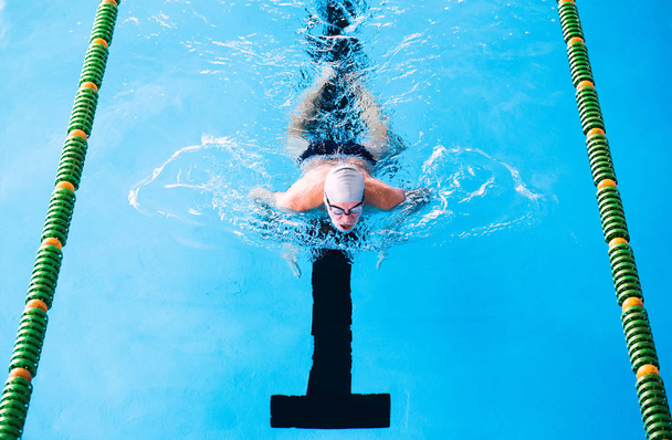 Senior man swimming in an indoor swimming pool. - 写真・画像