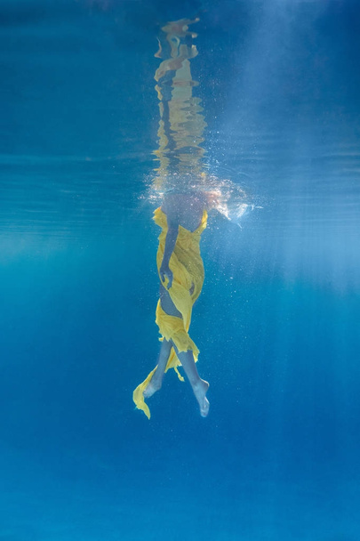 partial view of woman in dress swimming underwater - Zdjęcie, obraz