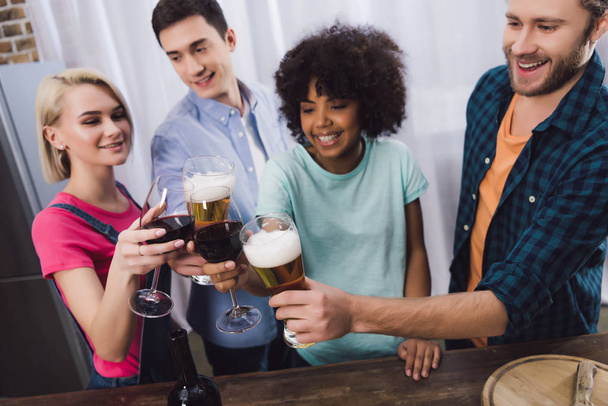 overhead view of multiethnic friends clinking with glasses of wine and beer - Фото, изображение
