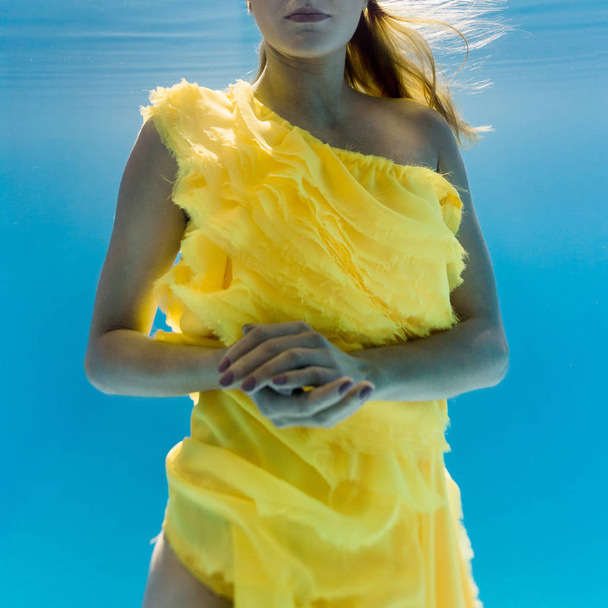частковий вид жінки в сукні, що плаває під водою
 - Фото, зображення