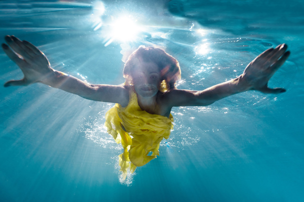 underwater picture of beautiful young woman in dress swimming in swimming pool - Фото, зображення