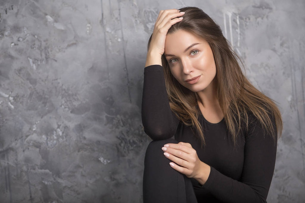 Young beautiful caucasian brunette woman sitting in casual clothes on a neutral background. Copy space - Fotó, kép