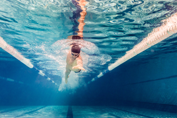 underwater picture of young swimmer in goggles exercising in swimming pool - Photo, Image