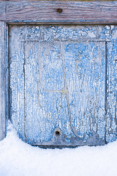 Peeling paint on the old door in the snow. A pattern of rustic blue grunge material. Abstract background. Texture - Fotografie, Obrázek