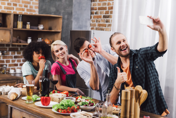 smiling multicultural friends taking selfie with smartphone in kitchen - Fotografie, Obrázek