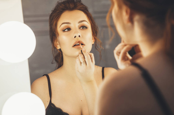 Brunette nainen soveltamalla meikki (maali hänen huulensa) varten ilta d
 - Valokuva, kuva