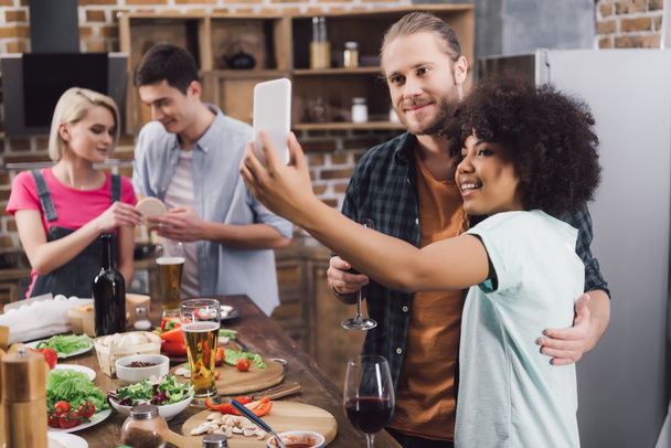 multiethnic friends taking selfie in kitchen with smartphone - Photo, image