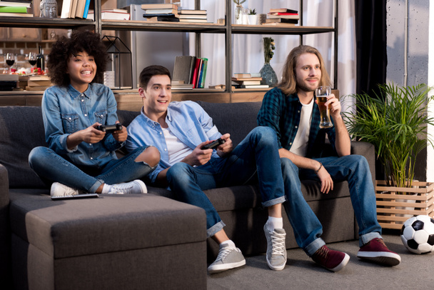 amici multiculturali che giocano al videogioco sul divano di casa
 - Foto, immagini