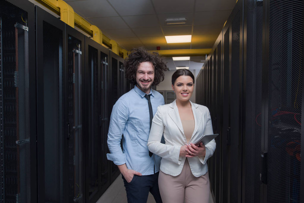 engineer showing working data center server room to female chief - Foto, Imagen