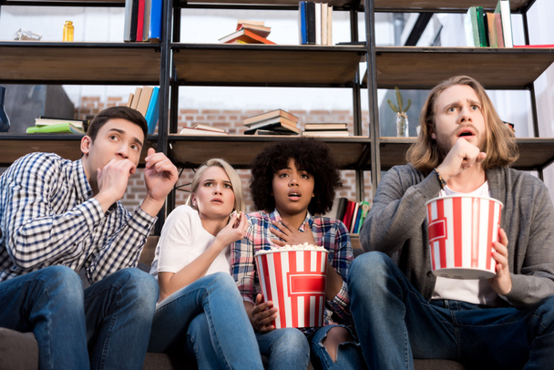 Shocked multiethnic friends watching horror movie with popcorn - Photo, Image
