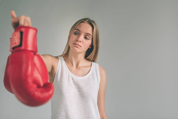 Cowardly funny young woman in red boxing gloves. Blond girl is wearing glasses - Fotó, kép