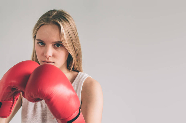 Cowardly funny young woman in red boxing gloves. Blond girl is wearing glasses - Fotografie, Obrázek