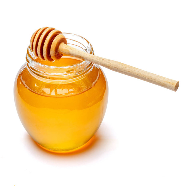 Glass can full of honey and wooden stick on a white background. clipping path - Φωτογραφία, εικόνα